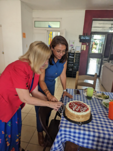 Two women cut a round cake